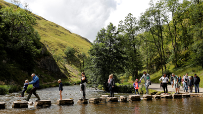 Walkers cross the Dovedale stepping stones in the Peak District in August 2017.