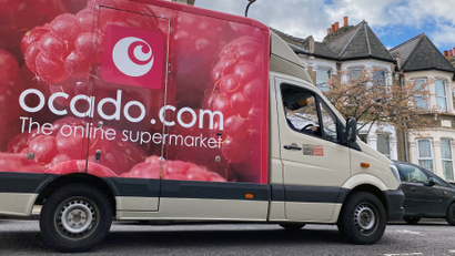 An Ocado delivery van drives down a London street.