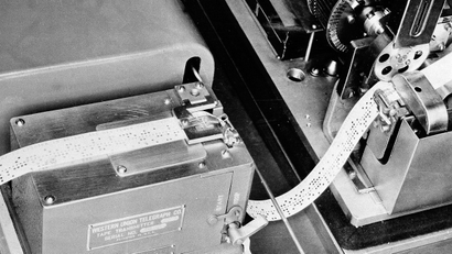 This is the current device used by Western Union which translates a telegram into holes on a tape, and then passes it along to the box-like apparatus at upper left, seen May 16, 1944.