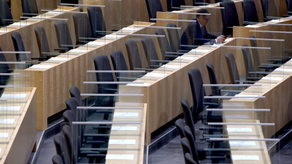 A member of the parliament sits between plexiglass shields ahead of the budget speech at the parliament in Vienna