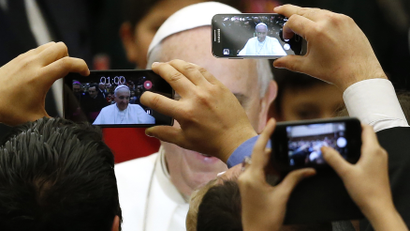 Pope Francis is pictured by mobile phones as he arrives to lead a special audience for Vatican employees and their families at the Paul VI's hall at the Vatican December 22, 2014. REUTERS/Alessandro Bianch