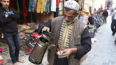 A coffee vendor pours a cup of coffee in Old Aleppo.