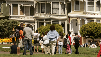 Visitors look at the skyline of San Francisco, including Victorian homes known as the "Painted Ladies," in San Francisco, California August 14, 2008.