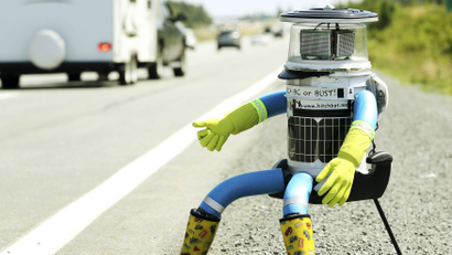 The anthropomorphic robot named hitchBOT sits on the shoulder of Highway 102 to begin its 6000 kilometer cross country journey outside of Halifax, Nova Scotia, July 27, 2014.