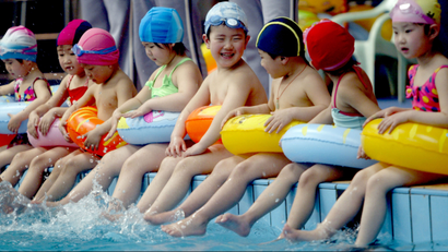 In this photo released by China's Xinhua News Agency, children sit along a pool as they take part in a swimming lesson, at the Natatorium of Shenyang, capital of northeast China's Liaoning Province, Monday, April 16, 2007. Youngsters from three to six are offered free swimming lessons at the natatorium. (AP Photo/Xinhua, Zhang Wenkui