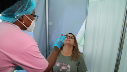 Healthcare worker collects a swab from Bronwen Cook for a PCR test against COVID-19 before traveling to London, at O.R. Tambo International Airport in Johannesburg