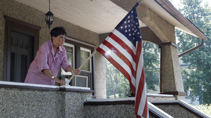 A woman places a US flag on her porch.