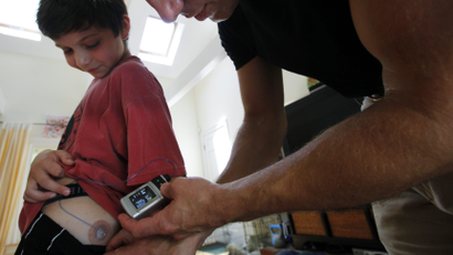 A father checks a child's insulin level on his wearable monitor