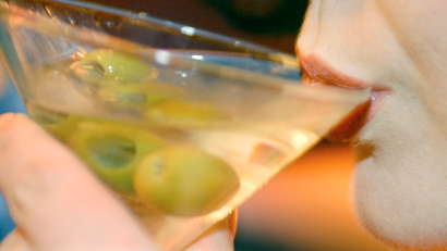 a woman sips a martini with olives in it