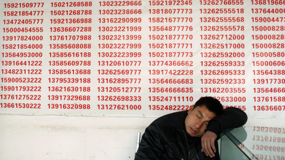 A man sleeps infront of a list of numbers