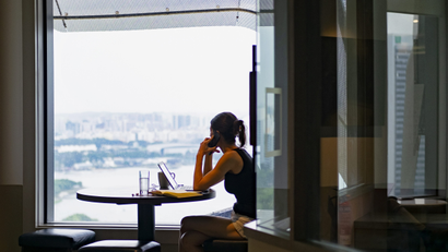 A woman answers a call while looking out the window in co-working space The Great Room's Centennial Tower location in Singapore
