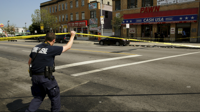 A police crime scene technician heads in to document evidence at the scene of a shooting at the intersection of West North Avenue and Druid Hill Avenue in West Baltimore, Maryland May 30, 2015.