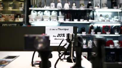 A sign announcing a discount is pictured at an Electroniki retail chain shop in Athens November 27, 2014. Greece has muddled through 20 consecutive months of deflation, or continuously falling consumer prices ? a phenomenon that economists say could soon infect the whole euro zone. In October, prices fell 1.7 percent from a year earlier. Yet alarm over low inflation in other parts of southern Europe does not echo in Greece. Economists say prices in Greece were unreasonably high for a long time. Between 1995 and 2010, consumer prices rose 17 percent more in Greece than in the euro area overall. Lower prices have since made Greek products more attractive. The sign reads " 20 percent discount to all washing machines". Picture taken November 27, 2014. REUTERS/Alkis Konstantinidis (GREECE - Tags: BUSINESS POLITICS)