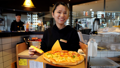 A waiter poses with a durian pizza at La Cesar Pizzaria in Shanghai