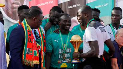 Senegal's president Macky Sall is on stage with a smiling Sadio Mane, with team captain Kalidou Koulibaly holding the Afcon trophy.