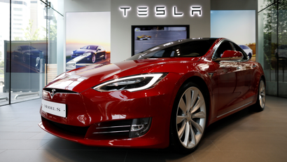 A Tesla Model S sedan gleams on the floor of a car dealership.