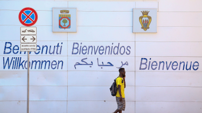 An African migrant walks near a sign reading "welcome" in different languages at the Foggia train station, Italy August 7, 2018. Picture taken August 7, 2018.
