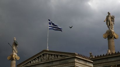 A Greek national flag flutters atop the university building as dark clouds fill the sky in Athens, Greece, June 30, 2015.