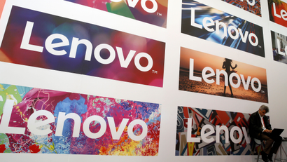 A man uses his laptop next to Lenovo's logos during the Mobile World Congress in Barcelona