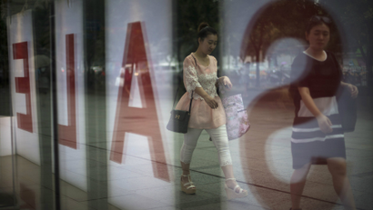 Women walk past a fashion outlet offering a sale at a shopping mall in Beijing.
