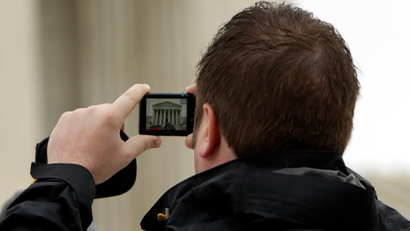 A man takes a picture with his mobile device outside of the U.S. Supreme Court in Washington April 29, 2014. The U.S. Supreme Court on Tuesday confronts the question of whether the increasing amount of deeply personal information kept on mobile devices means police officers need a warrant before they can search an arrested suspect's cell phone.