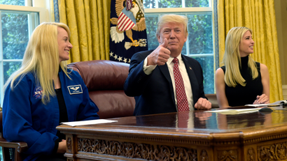 President Donald Trump, flanked by NASA astronaut Kate Rubins, left, and his daughter Ivanka Trump, gives a thumbs up following a video conference with the International Space Station, Monday, April 24, 2017, from the Oval Office of the White House in Washington.