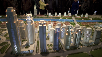 A guide introduces city planning details for a group of visitors at a model of a planned new city zone to be developed by 2020 at the Tianjin Planning Exhibition Hall in Tianjin, China, Tuesday, Feb. 28, 2012. China needs a new economic strategy after three decades of rapid growth and must reduce the dominance of state companies and promote free markets to achieve its goal of becoming a high-income society, the World Bank and Chinese researchers said Monday.