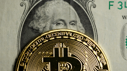 A physical bitcoin overlaid on a US dollar