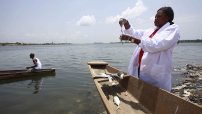 An African researcher in a canoe collecting water samples.