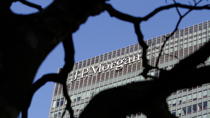A sign on the Canary Wharf offices of JP Morgan is seen through the branches of a tree in London