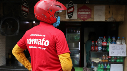 A delivery worker of Zomato waits to collect order outside an eatery in Kolkata