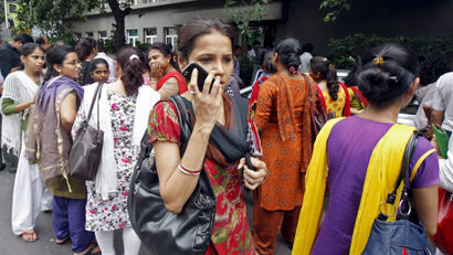 A woman speaks on her mobile phone as she stands with others after vacating their office buildings following an earthquake in Kolkata