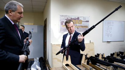 Russian Prime Minister Dmitry Medvedev (R) holds a weapon while listening to an explanation given by his deputy Dmitry Rogozin, during an inspection of Russian-made firearms at Promtechnologiya company in Moscow November 19, 2013.