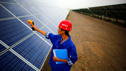 A worker inspects solar panels at a solar farm in China.