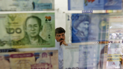 A man watches television inside his currency exchange shop in New Delhi