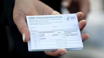 A medical worker holds Pfizer coronavirus disease (COVID-19) vaccination cards at a mobile vaccination drive for essential food processing workers at Rose &amp; Shore, Inc., in Vernon, Los Angeles