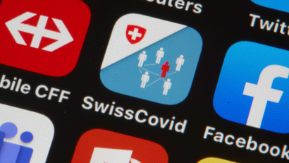 A phone screen displays the Swisscovid contact tracing application.