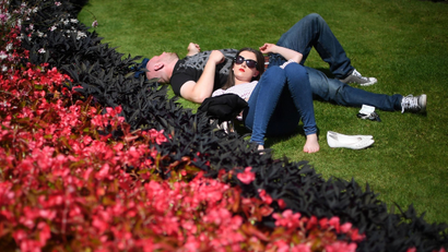 A man and a woman sleep on the grass, on a sunny day in Hyde Park, London