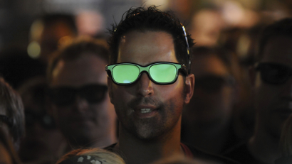 The pitch is reflected in a football fan's 3D glasses as he watches a live 3D TV football match in a pub in London