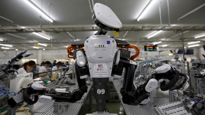 A humanoid robot works side by side with employees in the assembly line at a factory of Glory Ltd., a manufacturer of automatic change dispensers, in Kazo, north of Tokyo