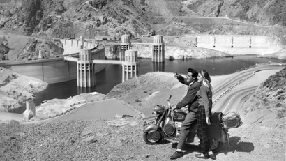 The mighty Hoover Dam impresses a young Swiss couple making their first tour of United States on their scooter, April 9, 1954 in Nevada. Natives of Zurich, Fred and Beatrice Troller were veteran scooter travelers in Europe before coming here.