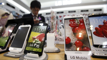 A sales assistant uses his mobile phone in front of mock LG electronics smart phones displayed at a store in Seoul July 22, 2014. South Korea's LG Electronics Inc said on July 24, 2014 its second-quarter profit rose 26.5 percent from a year earlier, beating analyst estimates, as the company's mobile business ran a profit for the first time in four quarters. Picture taken July 22. REUTERS/Kim Hong-Ji (SOUTH KOREA - Tags: BUSINESS TELECOMS)