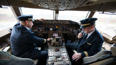 United Airlines Capt. Tommy Holloman, left, and Capt. Chuck Stewart demonstrate radio communications, right, and the Data Communications Data Comm technology, left, from the cockpit of an United Airlines Boeing 777