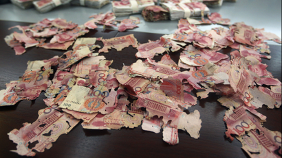 Damaged 100 yuan banknotes are seen on a table at a branch of China Bank in Foshan, Guangdong province, June 5, 2013. A woman brought about 400,000 yuan ($65,200), which she had kept at home, to the bank for replacement after most of the notes were bitten by white ants. Her notes were exchanged for new ones but for 60,000 yuan ($9,780) which the bank assessed and declared to be unchangeable. Picture taken June 5, 2013. REUTERS/Stringer