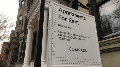 A Compass for-rent sign hangs on a townhouse in Brooklyn, New York.