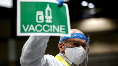 Dr. John Thayer holds up a sign to signal his station needs more vaccine doses.