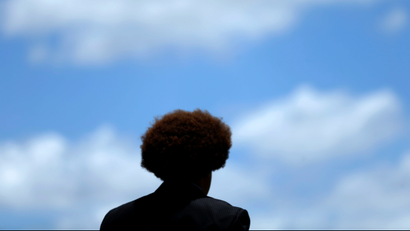 A young man silhouetted against a blue sky.
