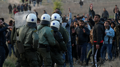 Riot police officers confront migrants and refugees in Greece