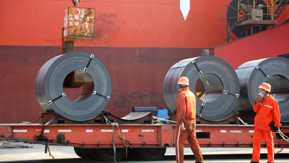 Workers load steel products for export to a cargo ship at a port in China