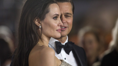 A side profile of Angelina Jolie as ex-husband Brad Pitt looks on.
